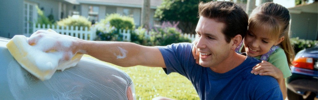 Father cleaning insured car with his daughter by his side.